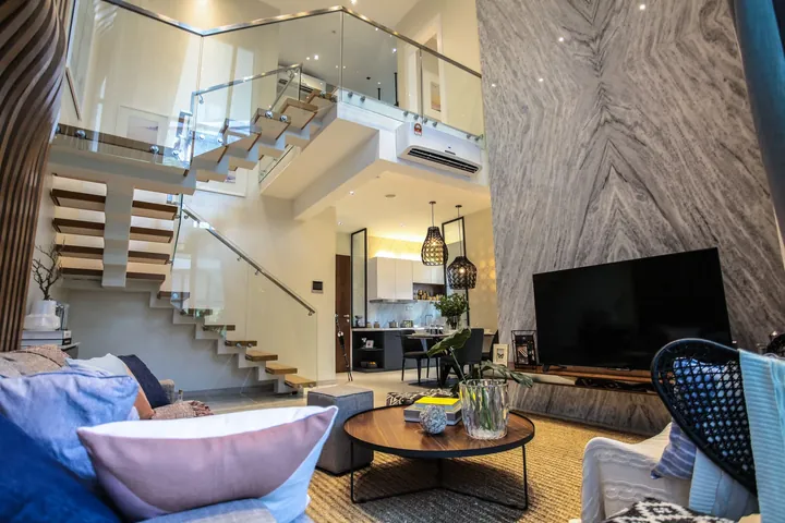 Double-height living room with a glass staircase in the Macrolink Medini duplex show unit