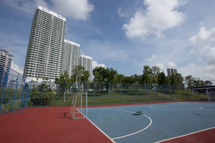 Macrolink Medini towers rising behind a sports court and lawn in the central park